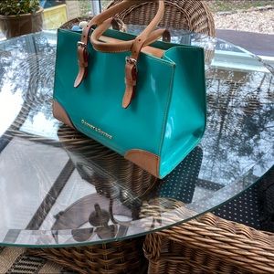 Dooney and Bourke turquoise patent leather purse with crossbody strap included.